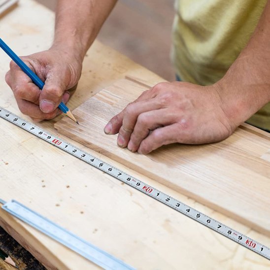 Mètre ruban étalé sur une planche de bois clair pour mesure de précision