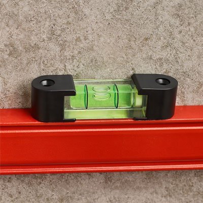 Niveau à bulle magnétique noir vert fixé sur barre métallique rouge - adhérence magnétique forte mesure précise

