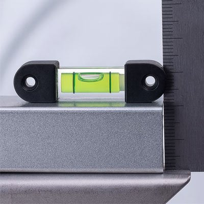 Niveau à bulle magnétique noir vert posé sur règle graduée métallique - outil mesure précision professionnelle
