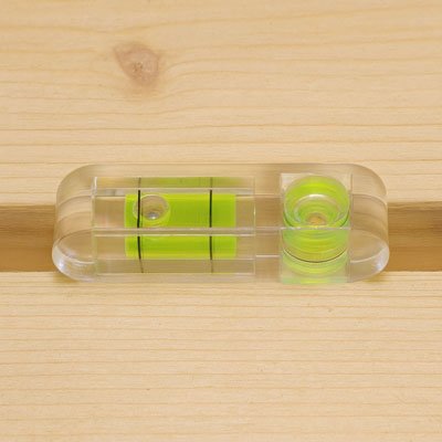 Niveau à bulle transparent 3 fioles vertes posé sur surface bois - outil alignement horizontal vertical 45°
