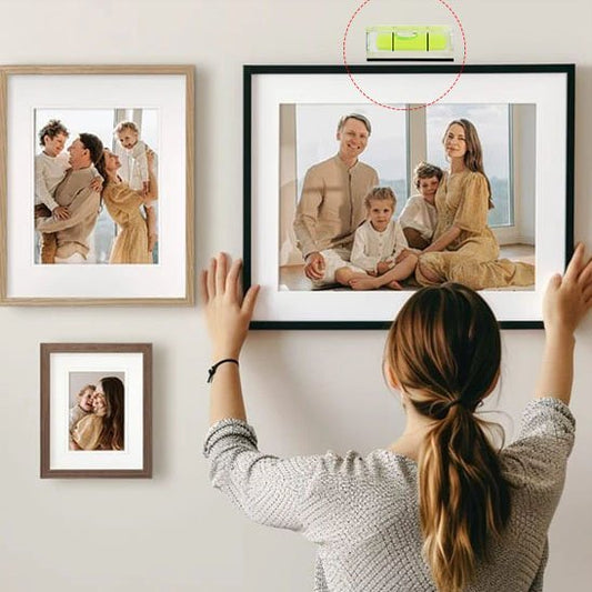 Femme utilisant porte-clés niveau à bulle pour accrocher cadre photo familial au mur