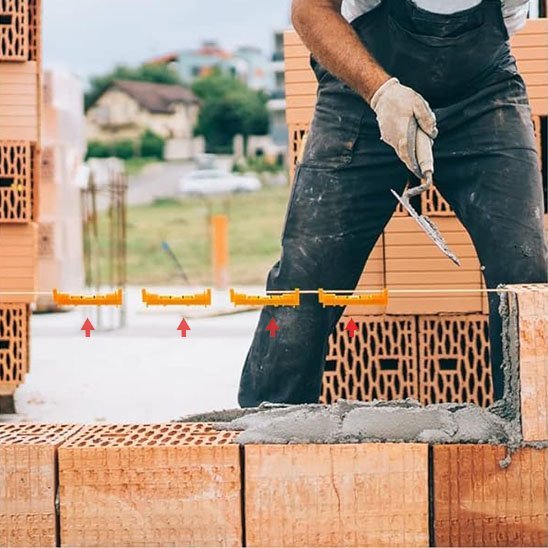 Maçon professionnel utilisant niveaux à bulle jaunes pour vérifier l'alignement des briques sur chantier