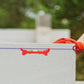 Niveau à bulle rouge fixé sur un muret blanc en extérieur avec gants de travail orange