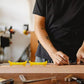 Artisan utilisant des niveaux à bulle jaunes sur une planche de bois dans un atelier