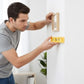 Homme utilisant niveau à bulle miniature jaune pour aligner cadre photo mural - mesure précision portable
