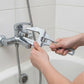 Clé à molette serrant un robinet de baignoire chromé