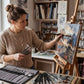 Femme peignant un tableau floral avec pinceaux professionnels en atelier
