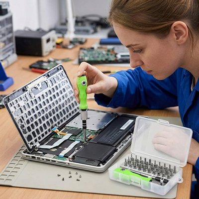 Femme technicienne démontant un laptop avec un kit tournevis de précision 32 en 1
