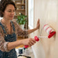 Femme utilisant un rouleau peinture pro rouge sur un mur intérieur