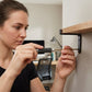 Femme vissant une étagère murale avec un tournevis hexagonal