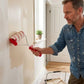 Homme appliquant de la peinture sur un mur de couloir avec un rouleau pro sans traces