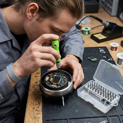 Homme réparant un appareil électronique avec un tournevis de précision 32 en 1