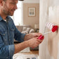 Homme souriant utilisant un rouleau peinture rouge pour rénover son intérieur