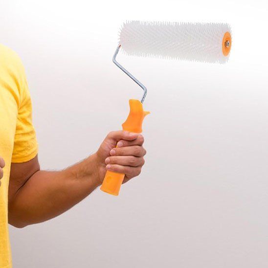 Homme tenant un rouleau peinture à picots blancs avec poignée orange