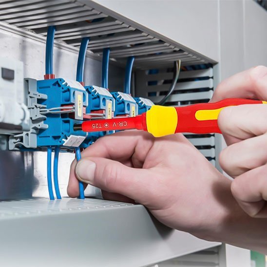 Électricien utilisant un tournevis isolé pour travaux électriques en toute sécurité