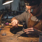 Artisan concentré utilisant marteau professionnel manche bois pour travaux précision sur métal atelier

