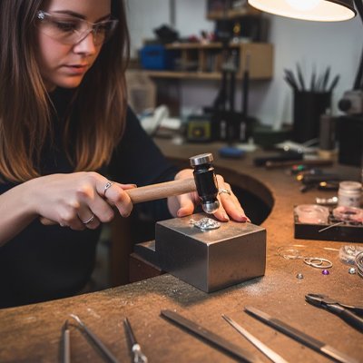 Artisane bijoutière utilisant marteau ergonomique manche bois pour création bijoux atelier professionnel
