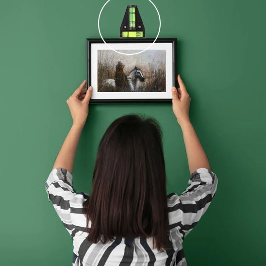 Femme accrochant cadre avec niveau à bulle triangle - installation précise décoration intérieure