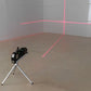 Niveau laser avec trépied projetant croix de nivellement rouge dans angle de pièce vide