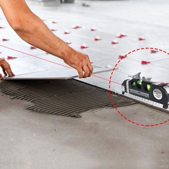 Artisan utilisant niveau laser pour pose précise de carrelage 