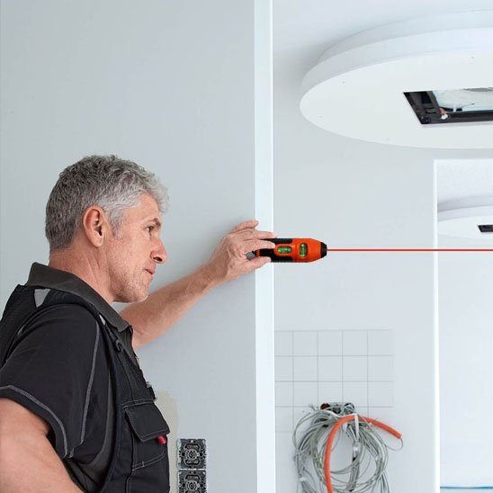 Niveau laser en utilisation sur chantier - projection ligne rouge horizontale sur mur