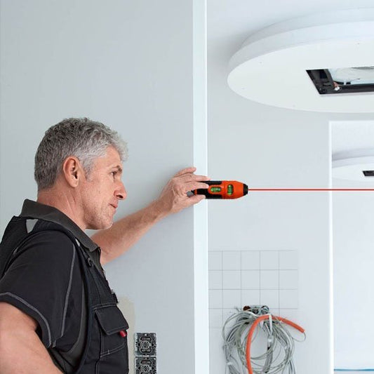 Niveau laser en utilisation sur chantier - projection ligne rouge horizontale sur mur