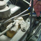 Pince à bec extra-longue manipulant un tuyau dans un moteur de voiture ancien