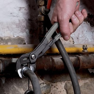 Main utilisant pince multiprise pour serrer tuyau industriel - poignées ergonomiques antidérapantes