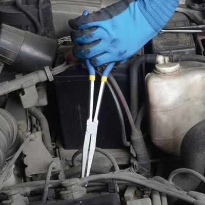 Technicien avec gants bleus utilisant une pince à bec extra-longue pour atteindre des câbles dans un moteur