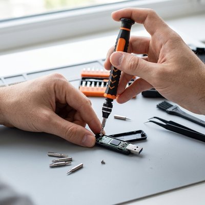 Technicien réparant une clé USB avec un tournevis de précision ergonomique
