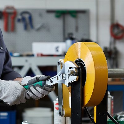 Clé à molette verte utilisée sur une machine industrielle jaune