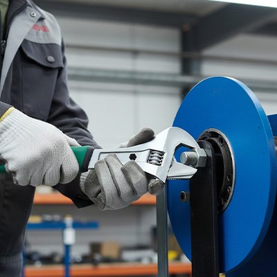 Clé à molette utilisée sur une machine industrielle bleue
