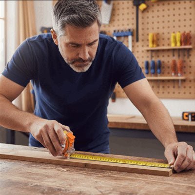 Homme utilisant un mètre ruban Précision Pro pour mesurer une planche de bois dans un atelier