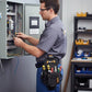 Électricien travaillant sur un tableau électrique avec porte-outils ceinture

