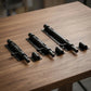 Loquet porte noir, trois modèles alignés sur table en bois