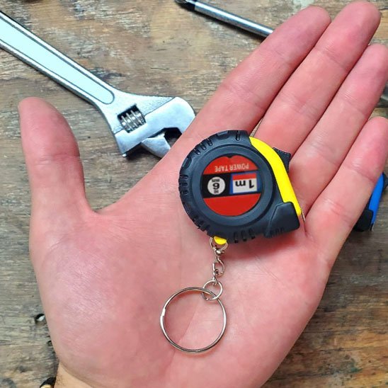 Mètre-ruban miniature porte-clés 1m Power Tape dans une main – coloris jaune/noir, taille compacte