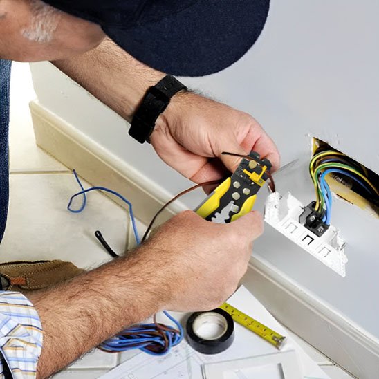 Électricien dénudant un câble avec pince à dénuder