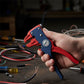Pince à dénuder rouge et bleue dénudant un câble tricolore sur un établi d'atelier