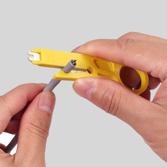 Mini pince à dénuder jaune dénudant un câble gris