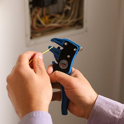 Pince à dénuder automatique bleue utilisée pour dénuder un câble électrique dans un tableau