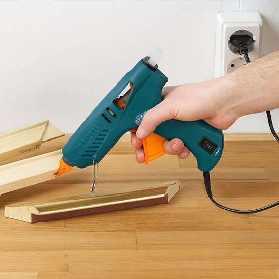 Pistolet à colle thermofusible utilisé pour coller des planches en bois sur un établi