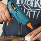 Pistolet à colle thermofusible bleu et orange en action sur un projet de bricolage