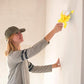Femme utilisant un rouleau peinture sur un mur en hauteur
