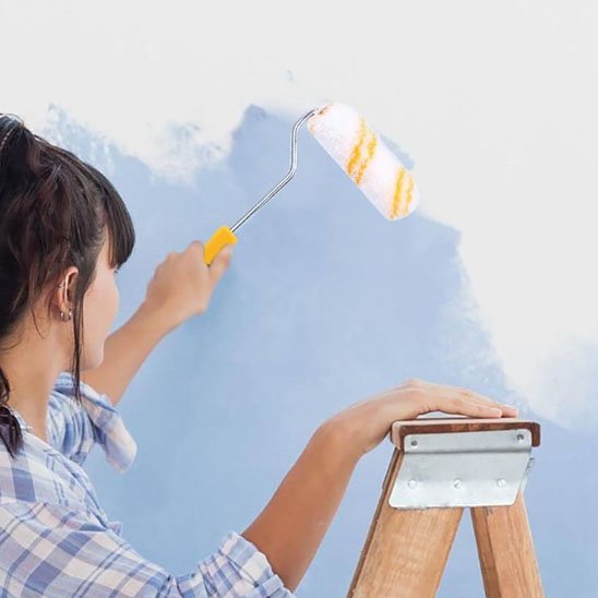 Rouleau peinture femme applique peinture bleue sur mur
