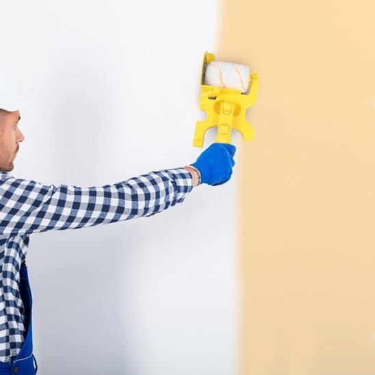 Rouleau peinture utilisé par un homme sur un mur beige
