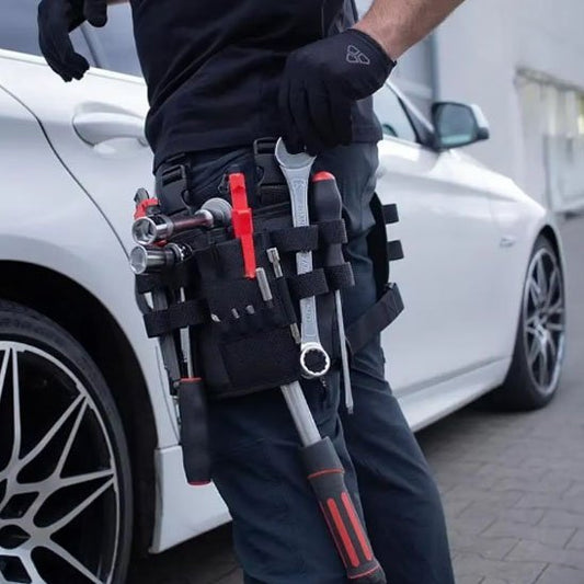 Mécanicien portant un sac à outils pour taille noir avec outils rouges et noirs, travaillant sur une voiture